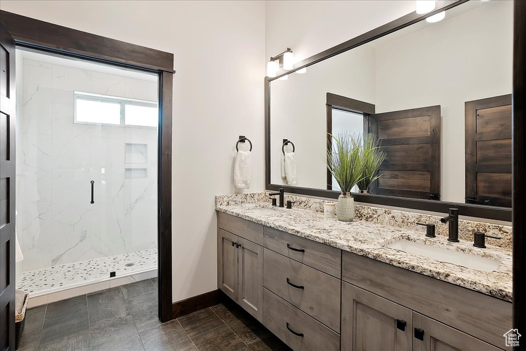 Bathroom with a marble finish shower, baseboards, and double vanity