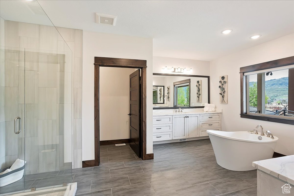 Full bath with a shower stall, vanity, a freestanding tub, recessed lighting, and tile patterned floors