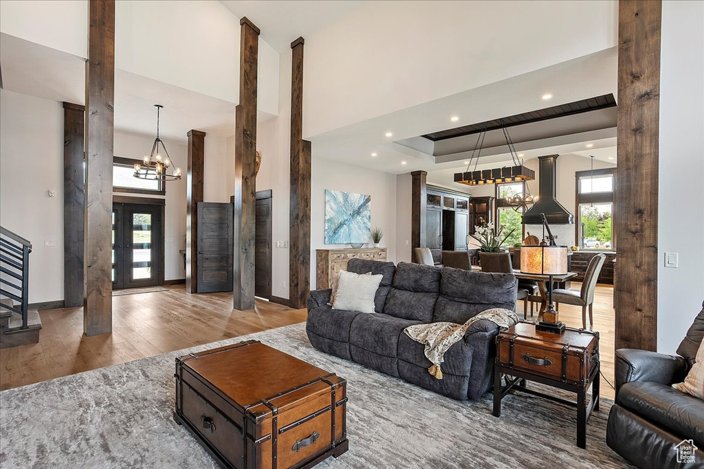 Living area with a chandelier, wood finished floors, stairs, a towering ceiling, and recessed lighting