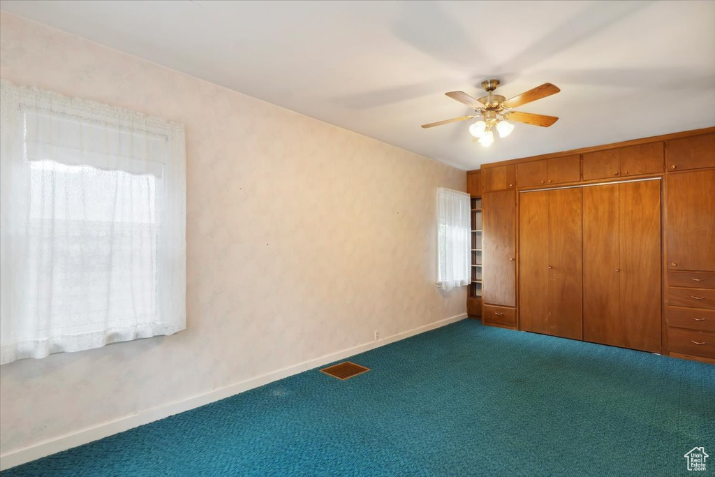 Unfurnished bedroom featuring dark colored carpet, baseboards, a closet, and a ceiling fan