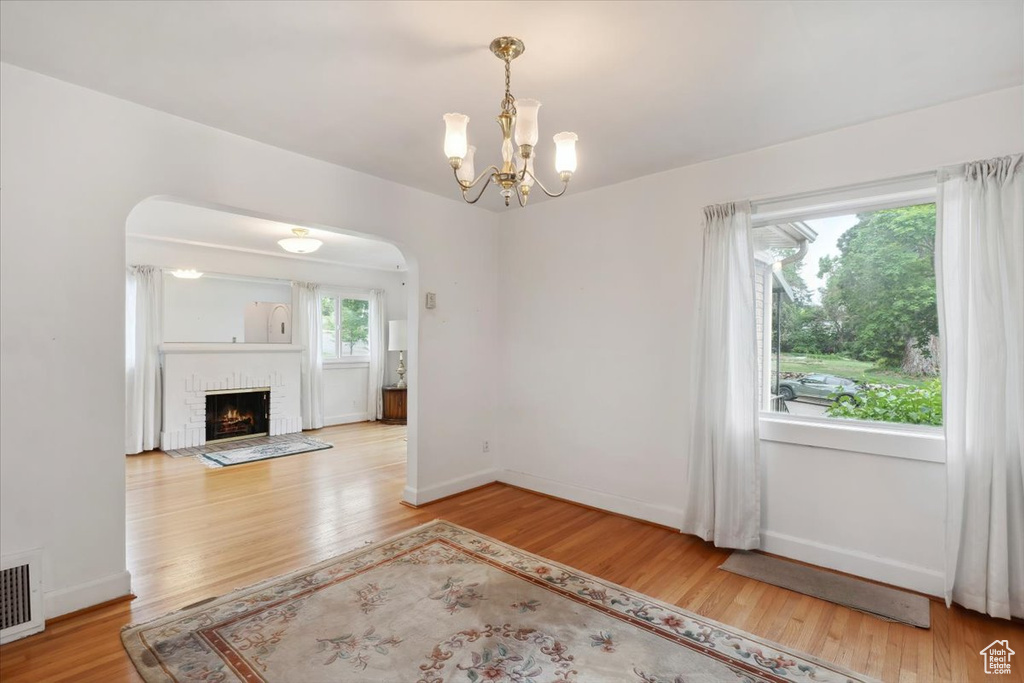 Unfurnished living room with wood finished floors, a chandelier, a fireplace, and baseboards