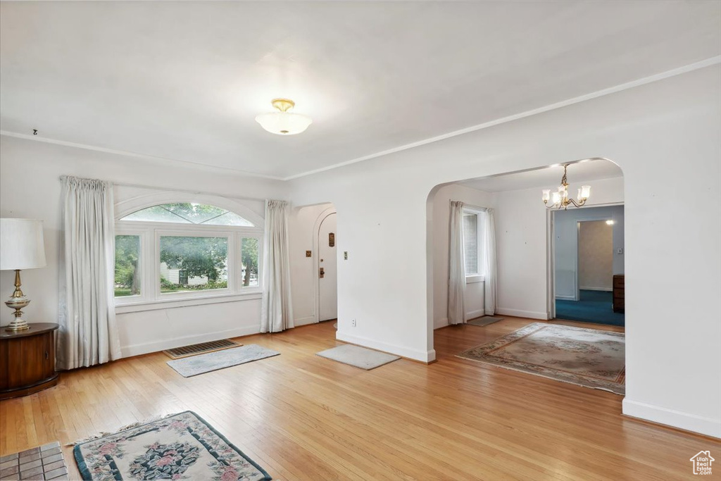 Entrance foyer featuring arched walkways, wood finished floors, a chandelier, and baseboards