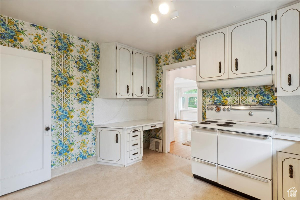 Kitchen with range with two ovens, wallpapered walls, light countertops, and baseboards