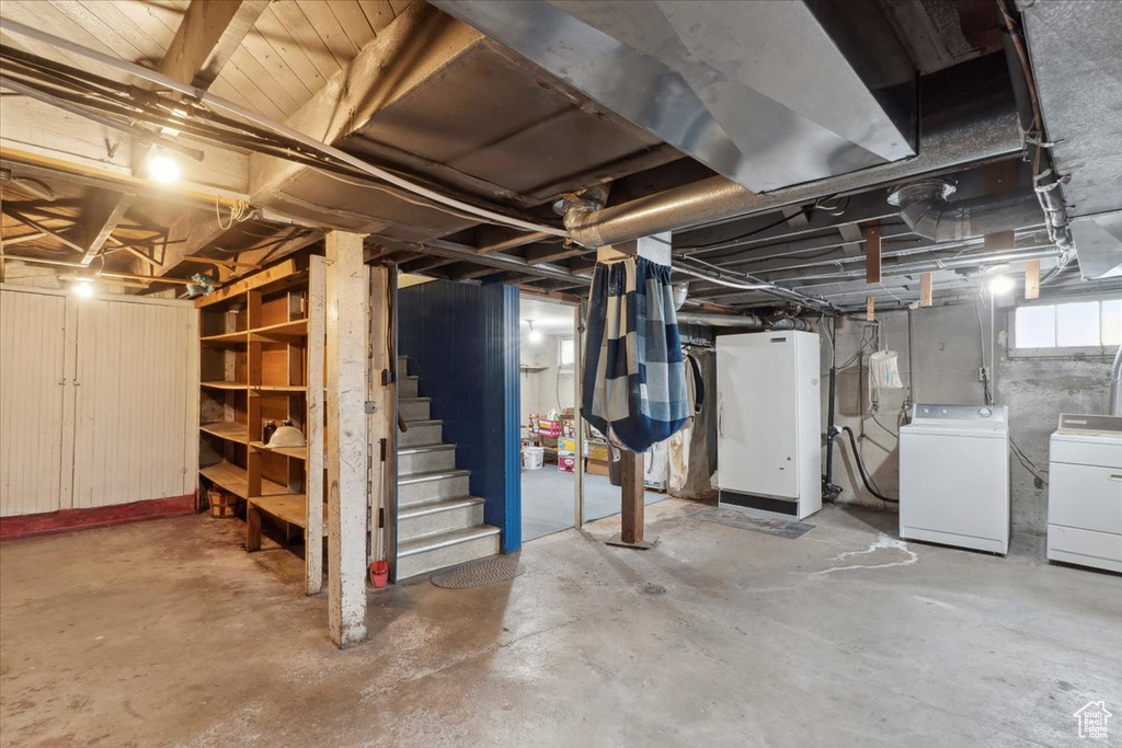 Basement featuring washing machine and clothes dryer and stairway