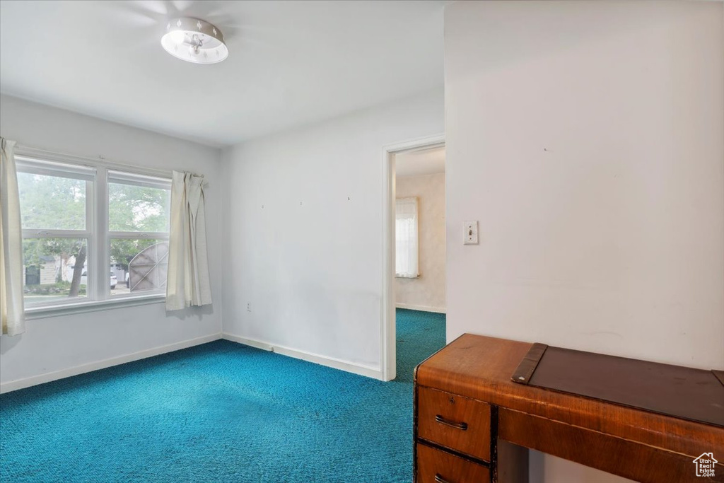 Empty room featuring dark carpet and baseboards