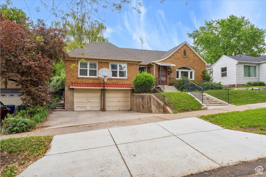 Bungalow with brick siding, driveway, a garage, and a shingled roof