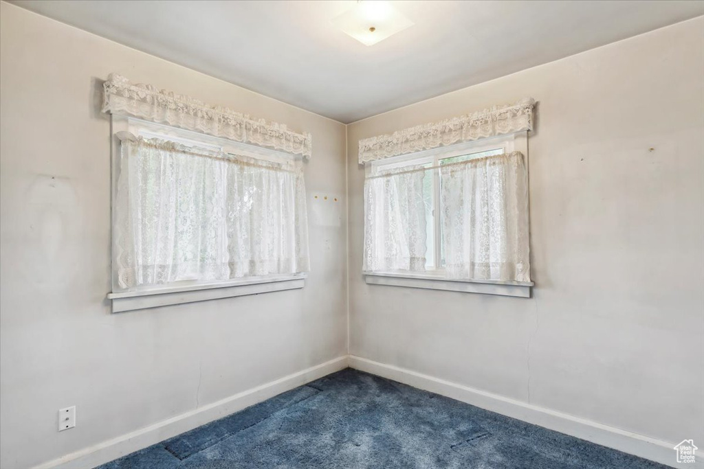 Spare room with dark carpet and baseboards