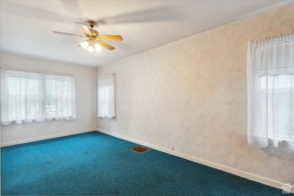 Spare room featuring carpet floors, a ceiling fan, and baseboards