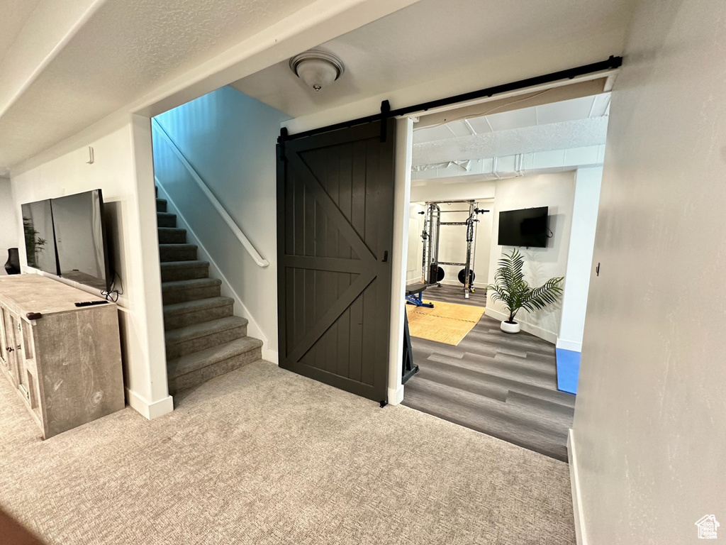 Finished below grade area featuring a barn door, baseboards, stairway, and wood finished floors