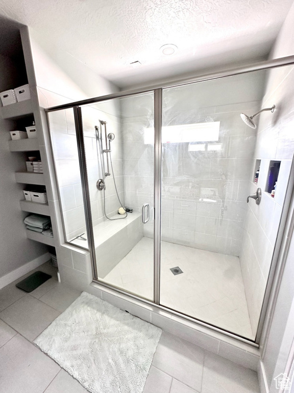 Bathroom with tile patterned floors, a textured ceiling, a stall shower, and baseboards