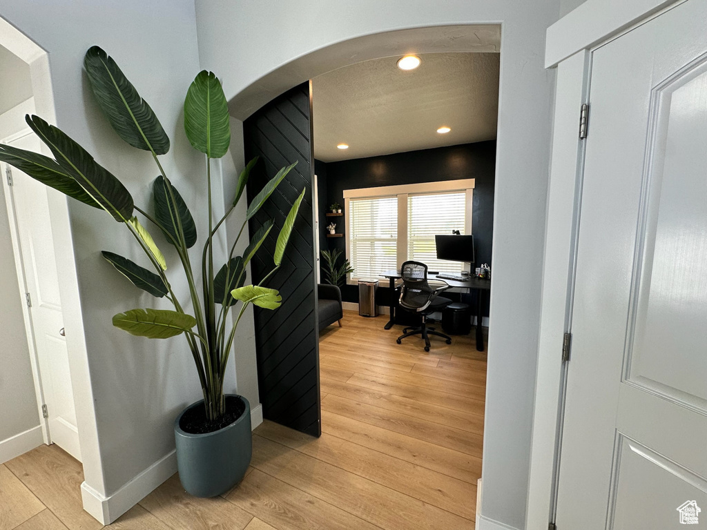 Office with arched walkways, light wood-style flooring, baseboards, and recessed lighting
