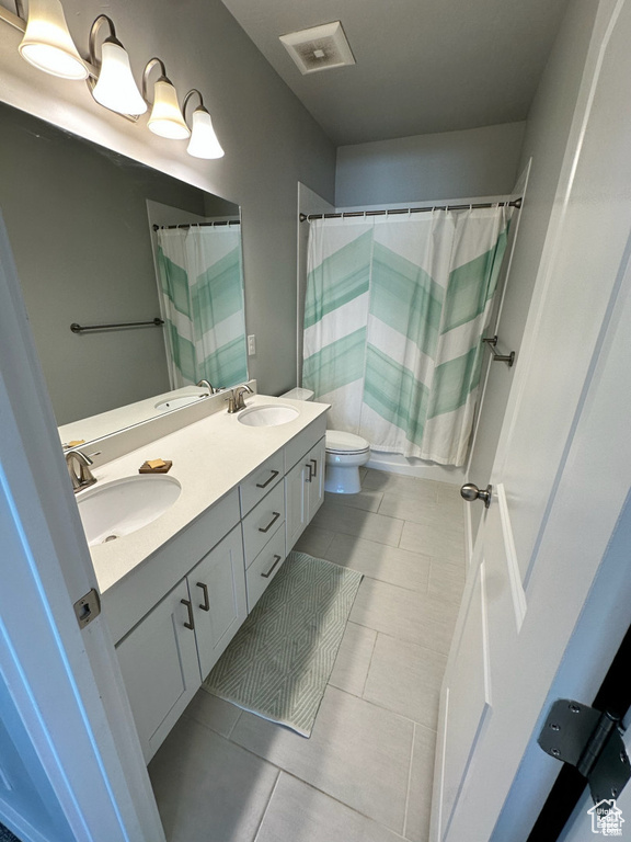 Bathroom with toilet, double vanity, curtained shower, and tile patterned floors