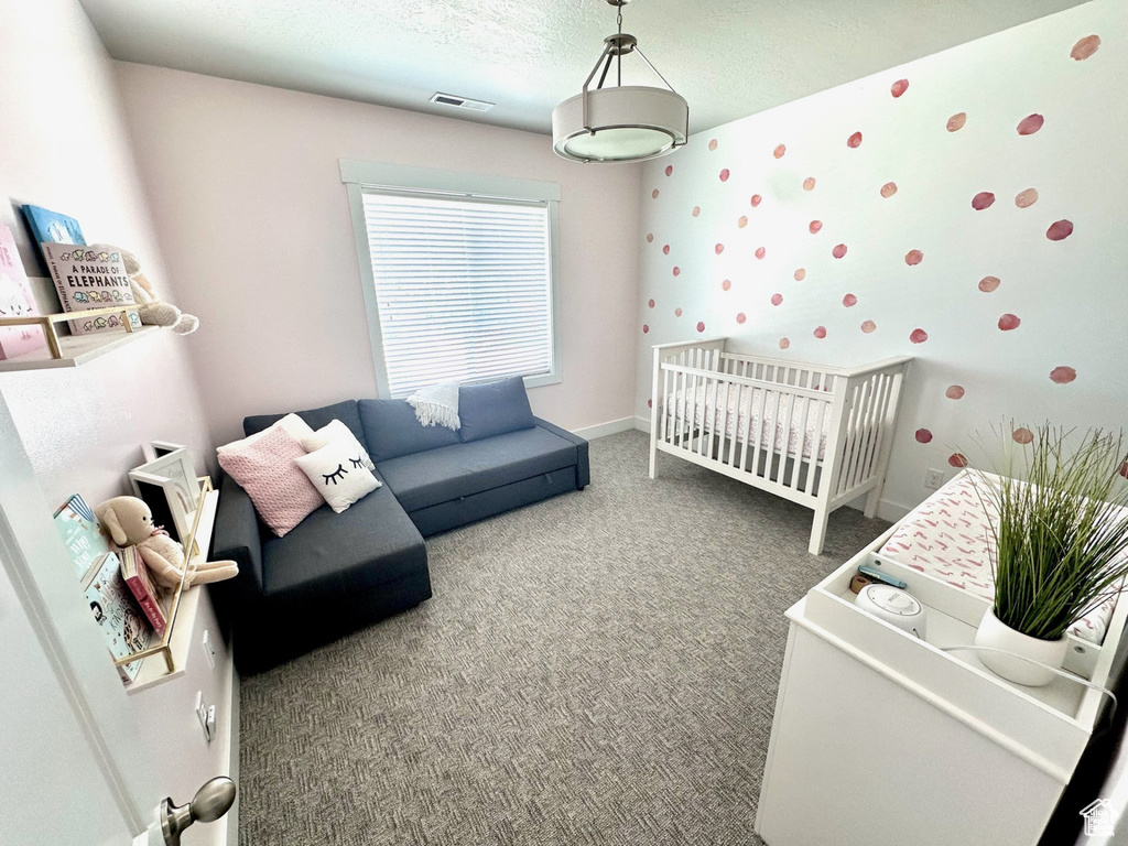 Carpeted bedroom featuring a crib