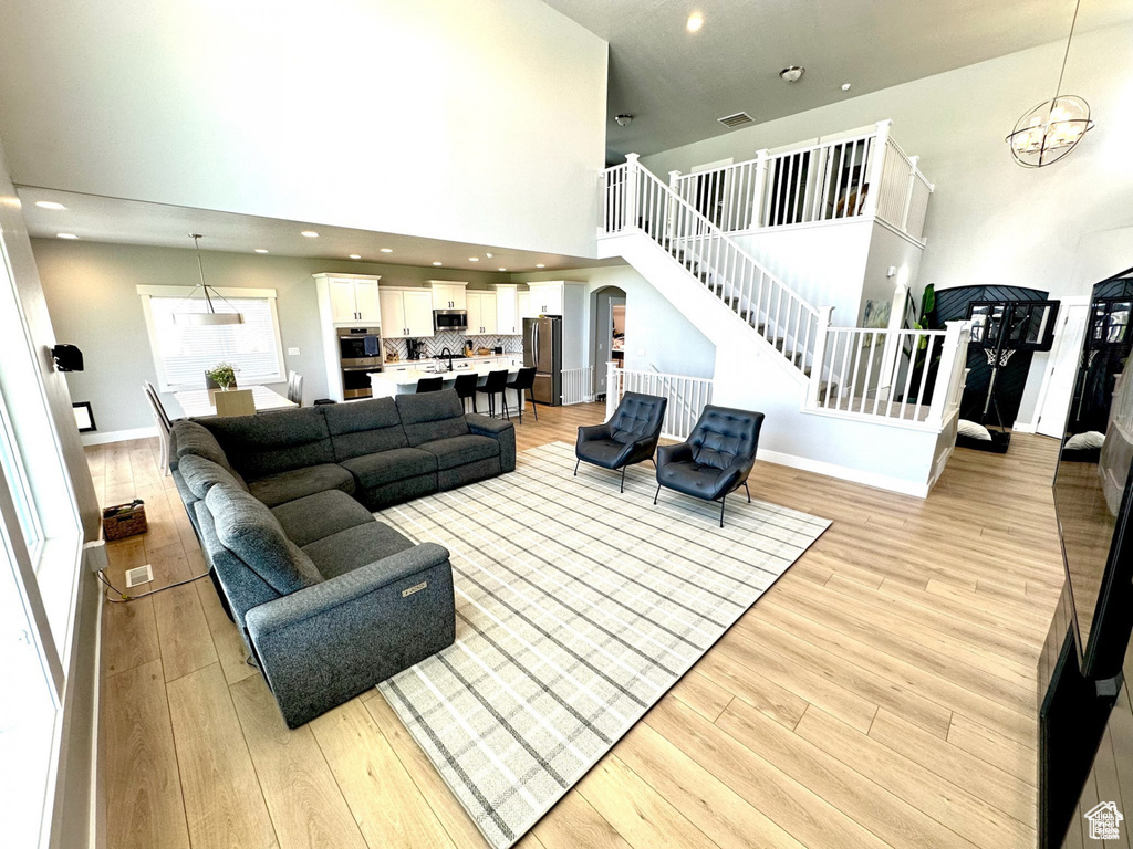 Living area featuring light wood-style floors, a high ceiling, stairs, arched walkways, and baseboards