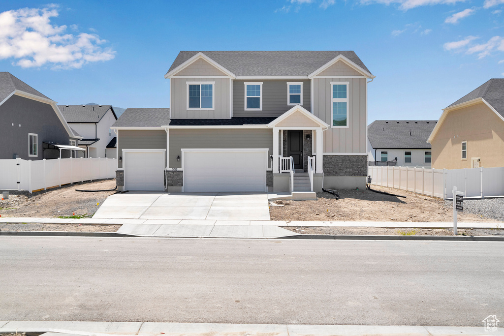 View of front facade featuring driveway, board and batten siding, and an attached garage