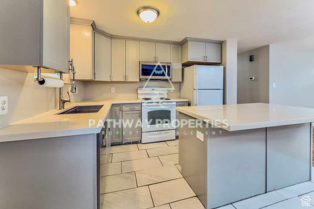 Kitchen featuring white appliances, gray cabinets, and light countertops