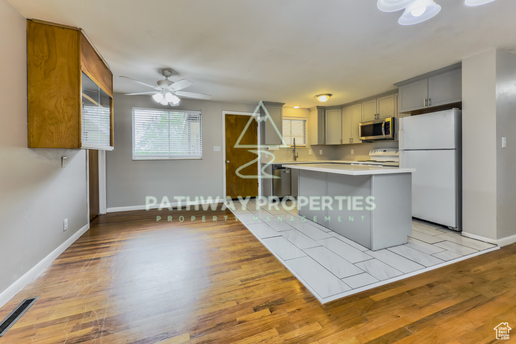 Kitchen featuring white appliances, light countertops, plenty of natural light, and ceiling fan