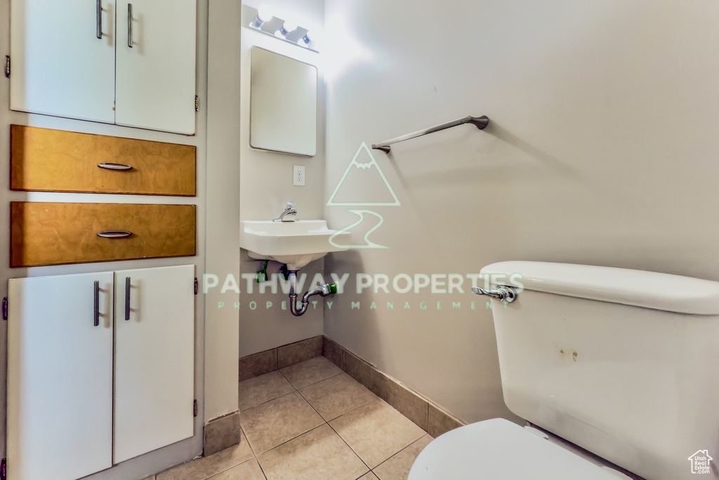Half bath featuring toilet, tile patterned floors, and baseboards