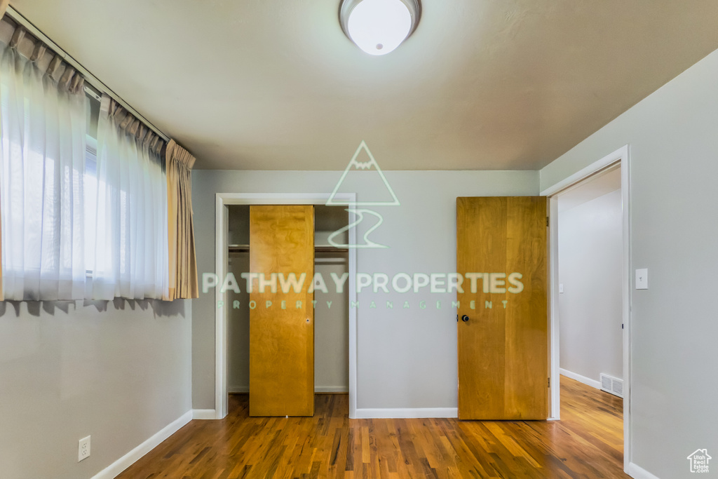 Unfurnished bedroom featuring baseboards, wood finished floors, and a closet