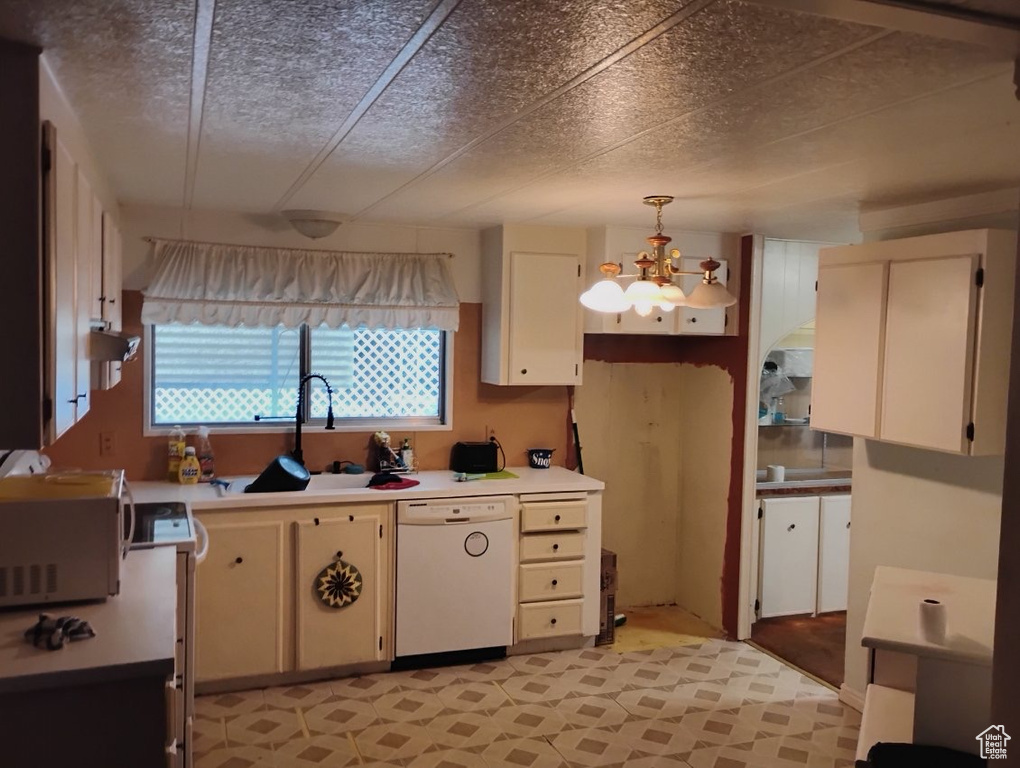 Kitchen with white appliances, a sink, light countertops, a chandelier, and hanging light fixtures