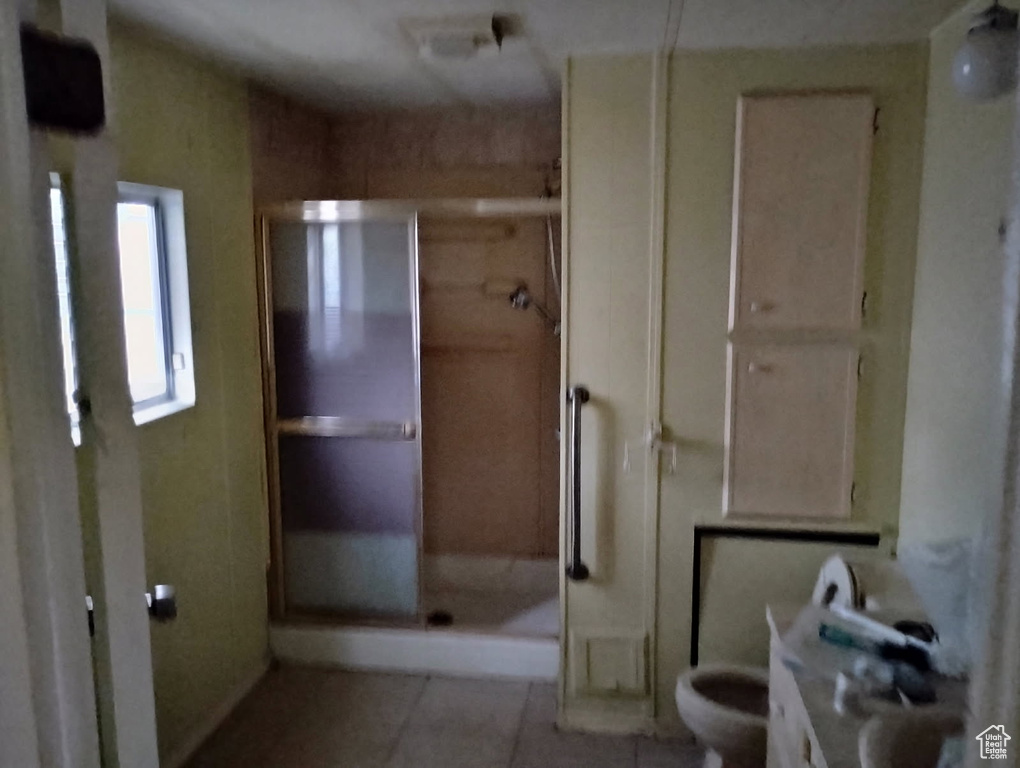 Full bath featuring a shower stall, tile patterned flooring, and toilet