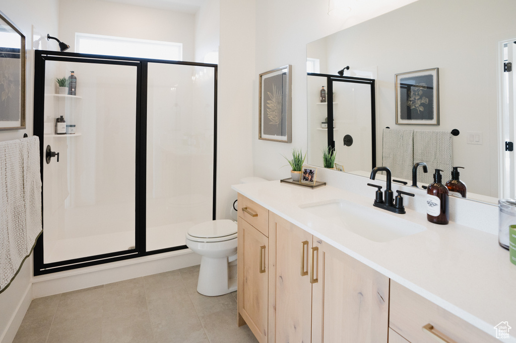 Full bath featuring a shower stall, vanity, toilet, and tile patterned floors