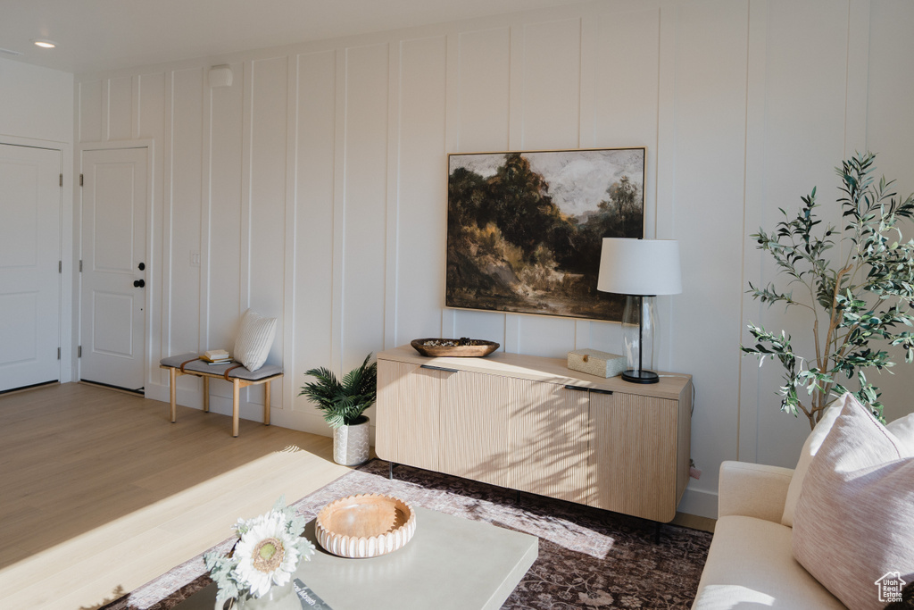 Living area with wood finished floors, a decorative wall, and recessed lighting