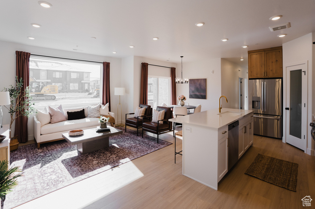 Kitchen with appliances with stainless steel finishes, a sink, open floor plan, light wood-type flooring, and a kitchen bar