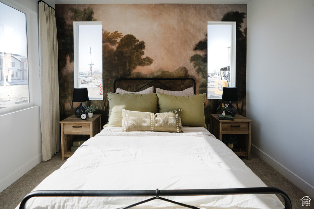 Carpeted bedroom with baseboards and multiple windows
