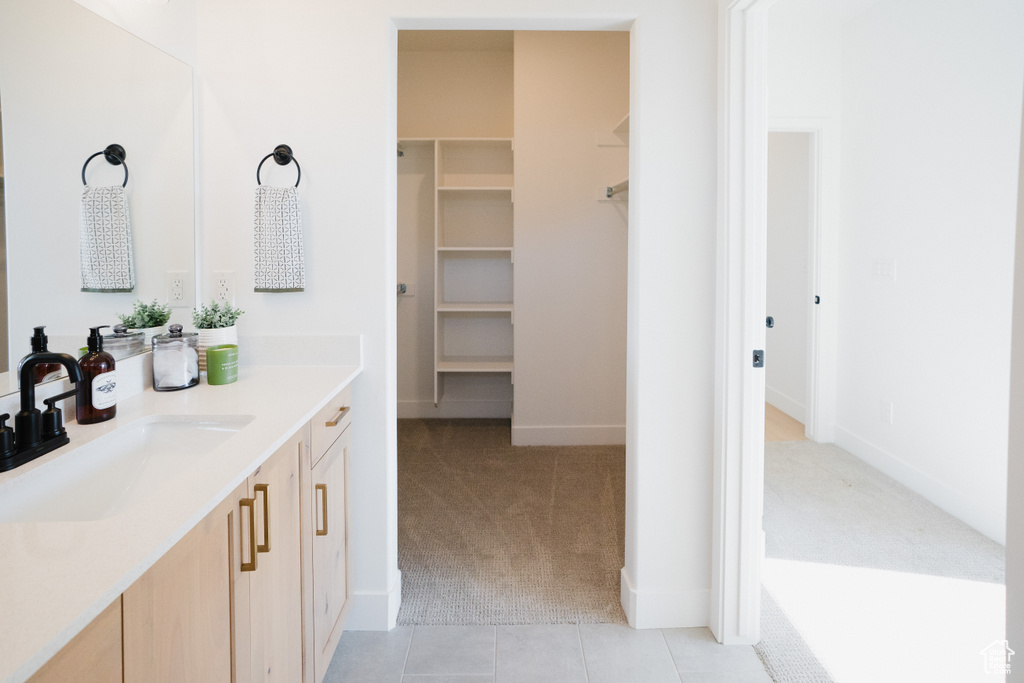 Bathroom featuring a spacious closet, tile patterned floors, vanity, and baseboards
