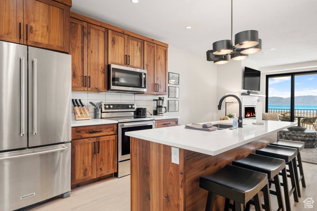 Kitchen with appliances with stainless steel finishes, brown cabinets, a sink, light countertops, and open floor plan