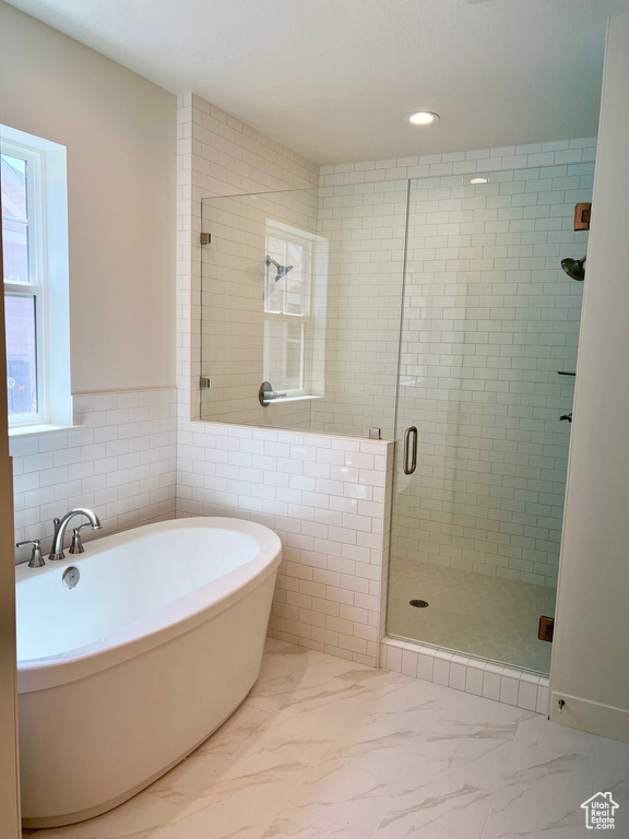 Bathroom featuring a soaking tub, a shower stall, marble look tile flooring, tile walls, and recessed lighting