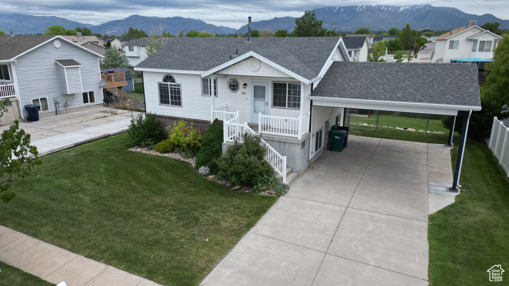 Ranch-style home featuring a carport, roof with shingles, concrete driveway, a mountain view, and a residential view