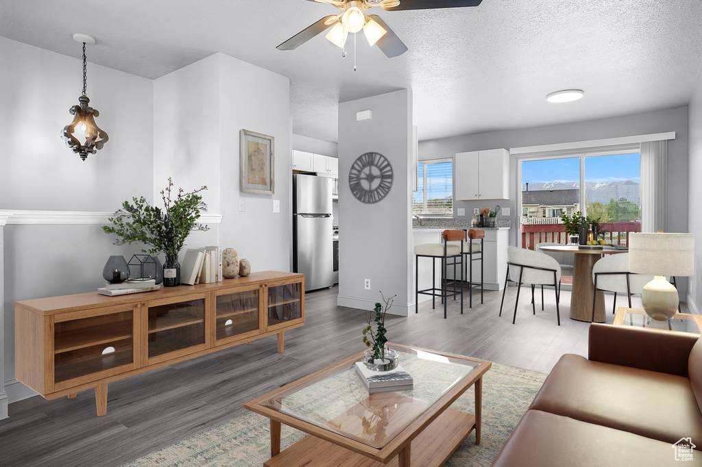 Living room with a ceiling fan, wood finished floors, and baseboards