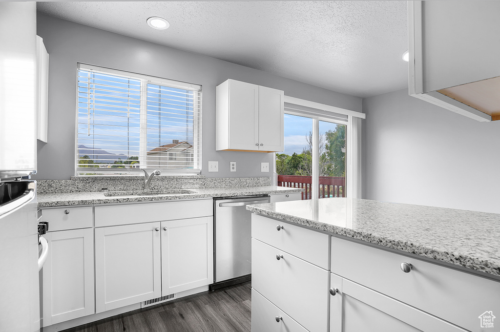 Kitchen featuring a sink, dishwasher, dark wood-type flooring, white cabinets, and a textured ceiling