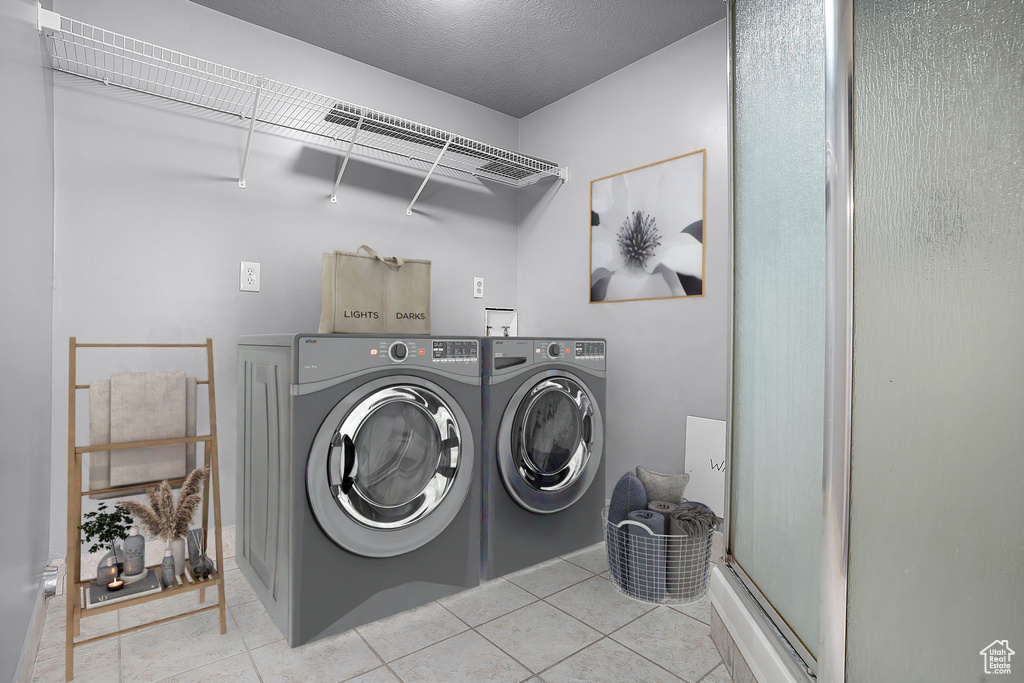 Laundry area with washer and clothes dryer and tile patterned floors