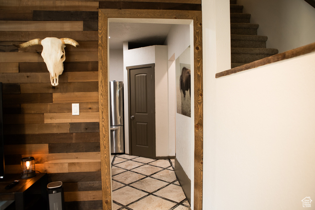 Hall featuring wooden walls, light tile patterned flooring, and stairway
