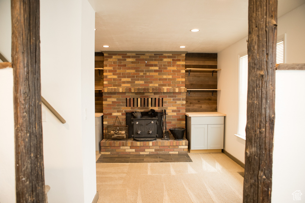 Unfurnished living room with a wood stove, recessed lighting, baseboards, and carpet