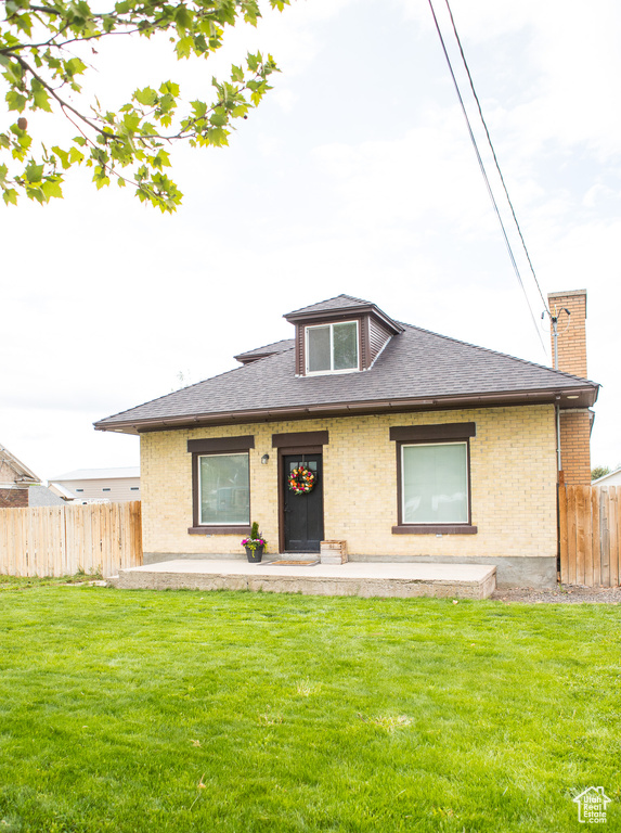 Bungalow featuring brick siding, a shingled roof, and a chimney