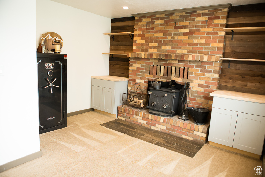 Unfurnished living room featuring a wood stove, light colored carpet, baseboards, and recessed lighting