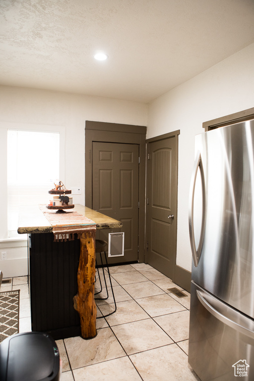 Kitchen with freestanding refrigerator, light tile patterned flooring, recessed lighting, and light countertops
