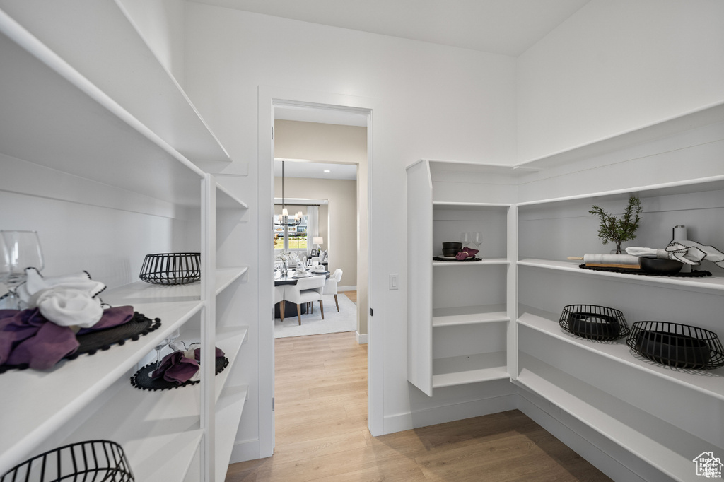 Spacious closet with light wood finished floors and a chandelier