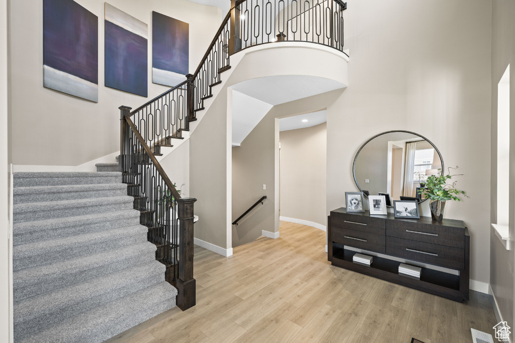 Stairs featuring a towering ceiling, baseboards, and wood finished floors