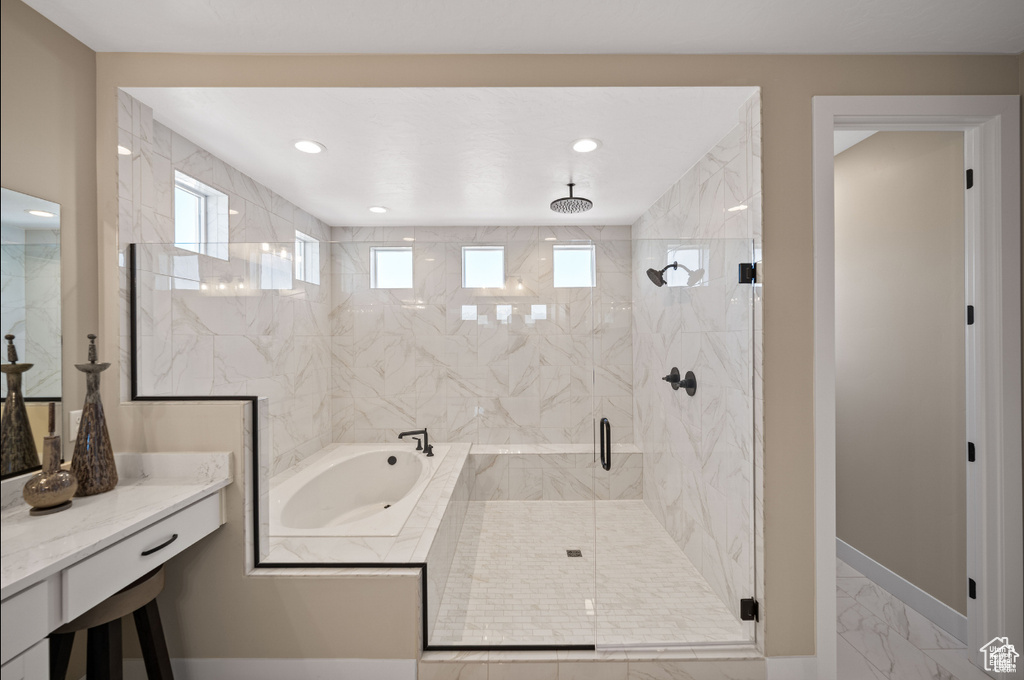 Bathroom with marble finish flooring, a shower stall, a garden tub, baseboards, and recessed lighting