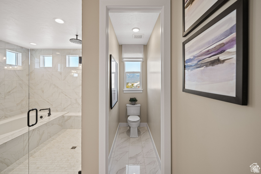 Bathroom with marble look tile flooring, a marble finish shower, toilet, and baseboards