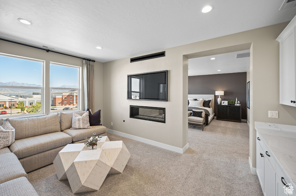Living area with light colored carpet, recessed lighting, baseboards, a mountain view, and a glass covered fireplace