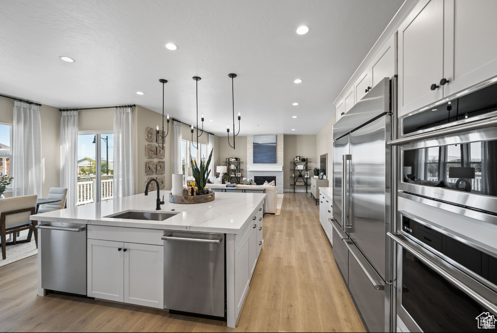 Kitchen featuring a sink, stainless steel appliances, open floor plan, a kitchen island with sink, and recessed lighting