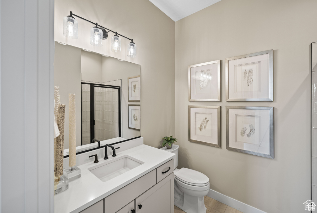 Bathroom with tiled shower, toilet, vanity, and baseboards