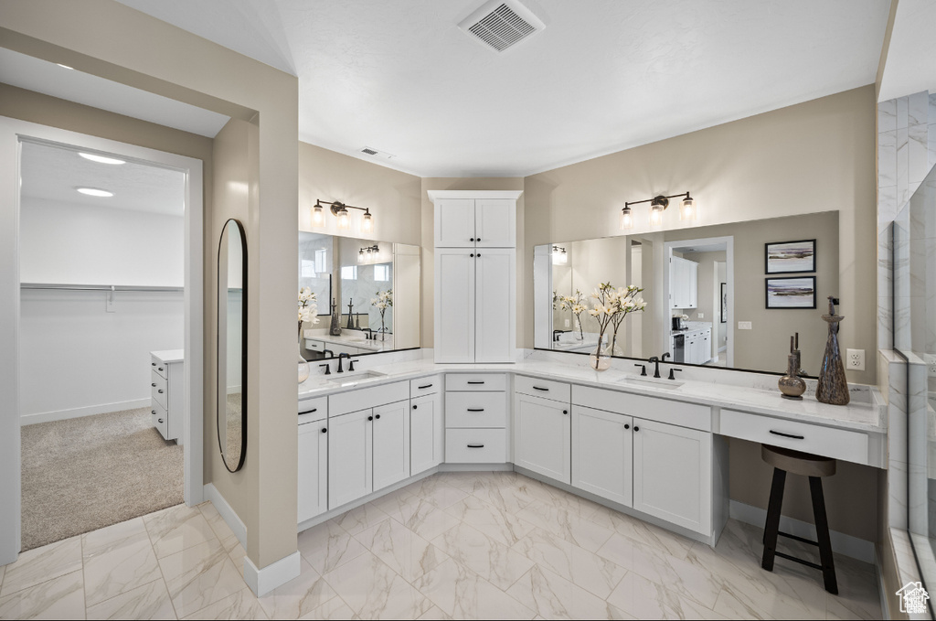 Bathroom with marble finish floors, vanity, baseboards, and a spacious closet