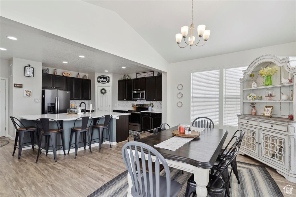 Dining space featuring a chandelier, vaulted ceiling, light wood-style flooring, and recessed lighting